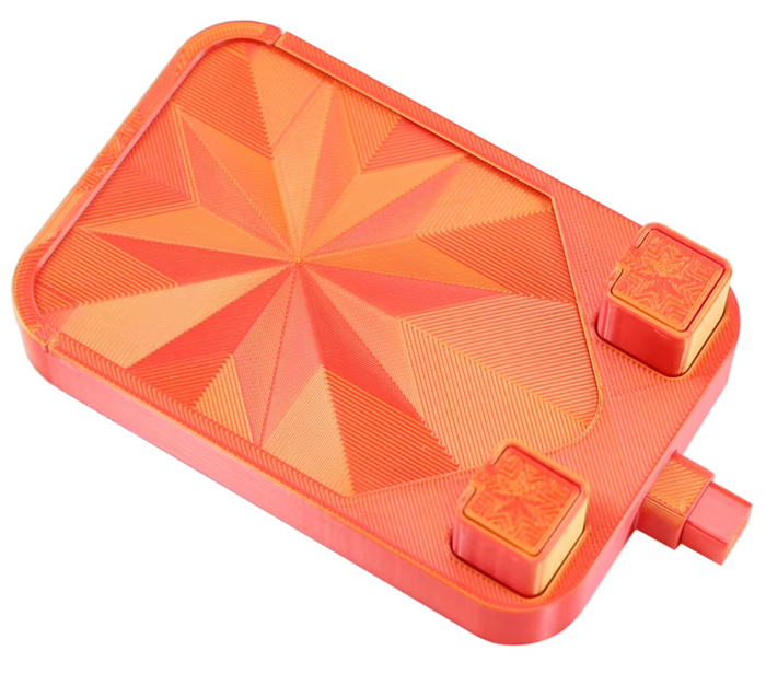 Orange diamond painting tray with its starburst lid snapped on, two drill cups in the corner wells and the pour spout