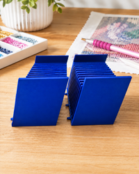 Pair of blue 3D printed 12-slot tilted drill packet trays on a craft table – image 4