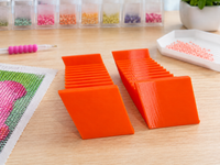 Pair of orange 3D printed 12-slot tilted drill packet trays on a craft table – image 6