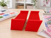 Pair of red 3D printed 12-slot tilted drill packet trays on a craft table – image 3
