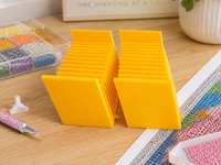 Pair of yellow 3D printed 12-slot tilted drill packet trays on a craft table – image 5