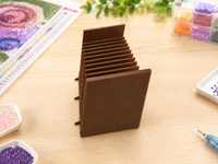 Coffee brown 3D printed 12-slot tilted drill packet tray on a craft table beside a diamond painting – image 9