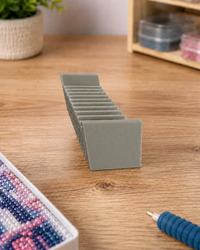 Grey 3D printed 12-slot tilted drill packet tray on a wooden craft table beside a diamond painting – image 2
