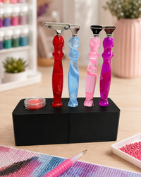 Black Drill Pen Station holding four resin drill pens, with wax in the wax well, on a craft table – image 5