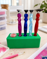 Green Drill Pen Station holding four resin drill pens, with wax in the wax well, on a craft table – image 11