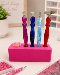 Pink Drill Pen Station holding four resin drill pens, with wax in the wax well, on a craft table – image 17