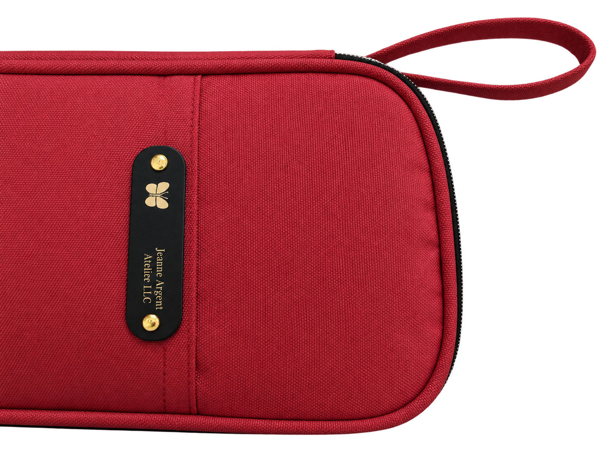 The Tool Keeper in true red, side view showing the soft wrist strap and Jeanne Argent label